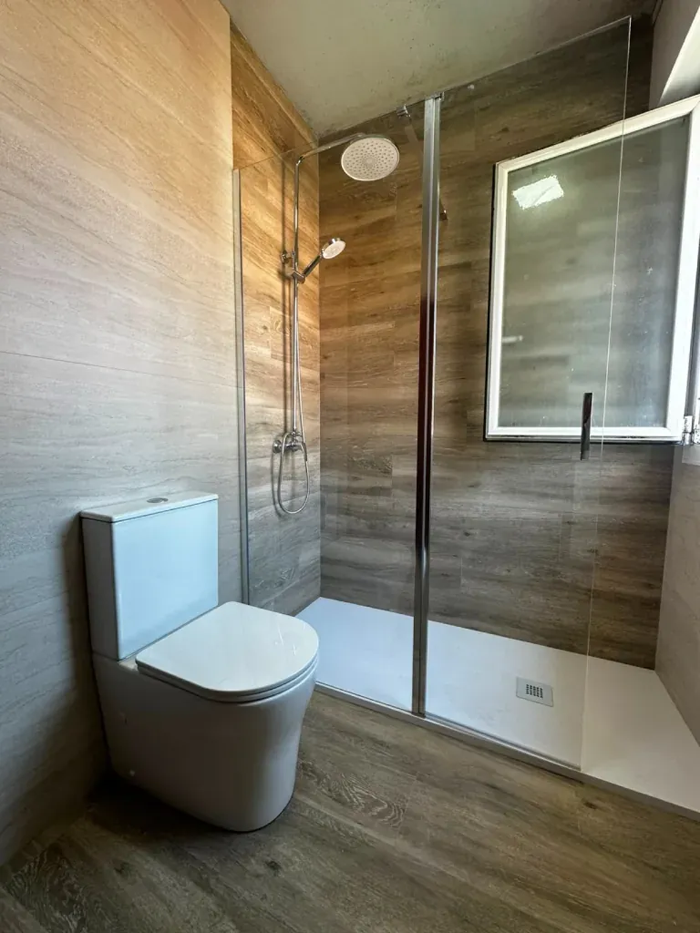 Zona de ducha con mampara y azulejo efecto madera