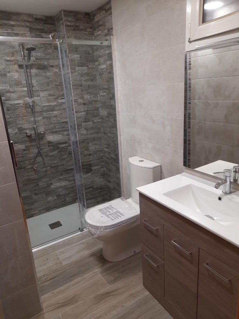 Mueble de lavabo de madera y ducha con revestimiento de piedra