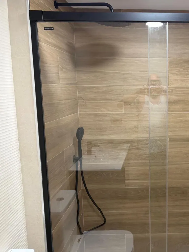 Ducha en tono gris piedra junto al mueble de lavabo