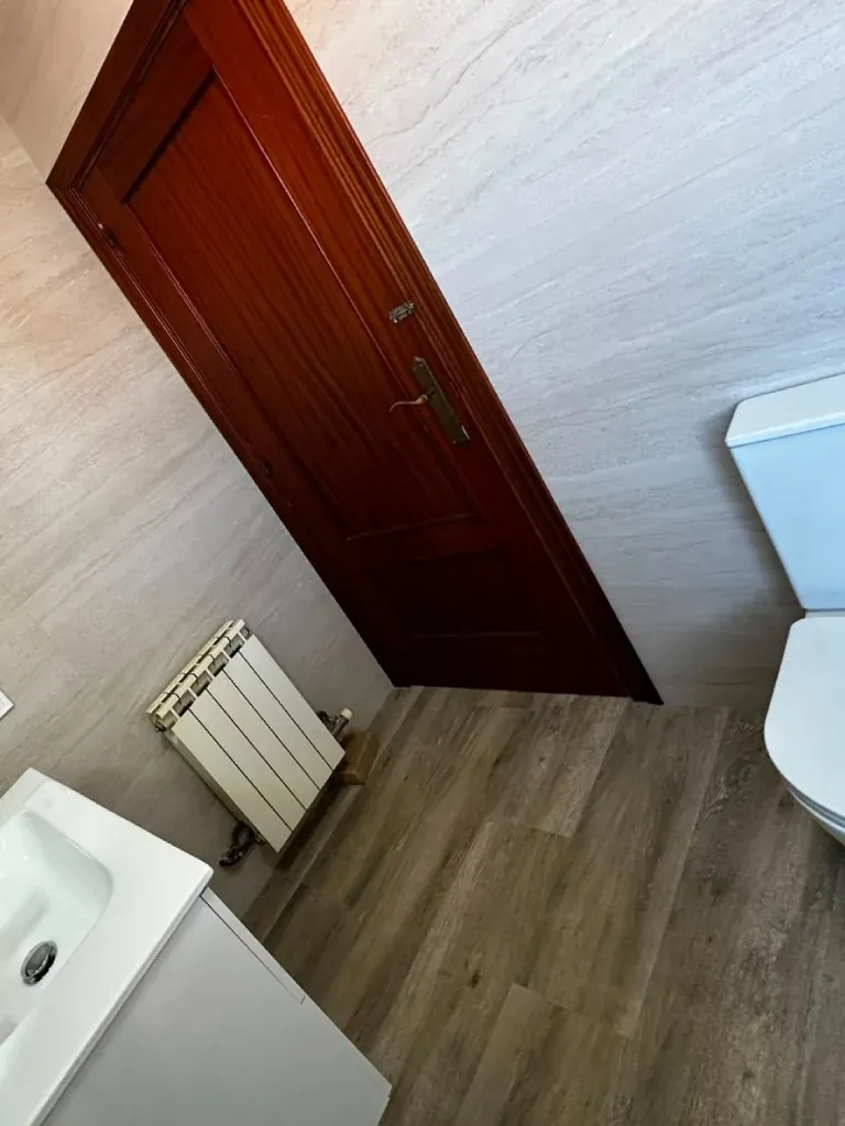 Baño renovado con toallero radiador y suelo de laminado